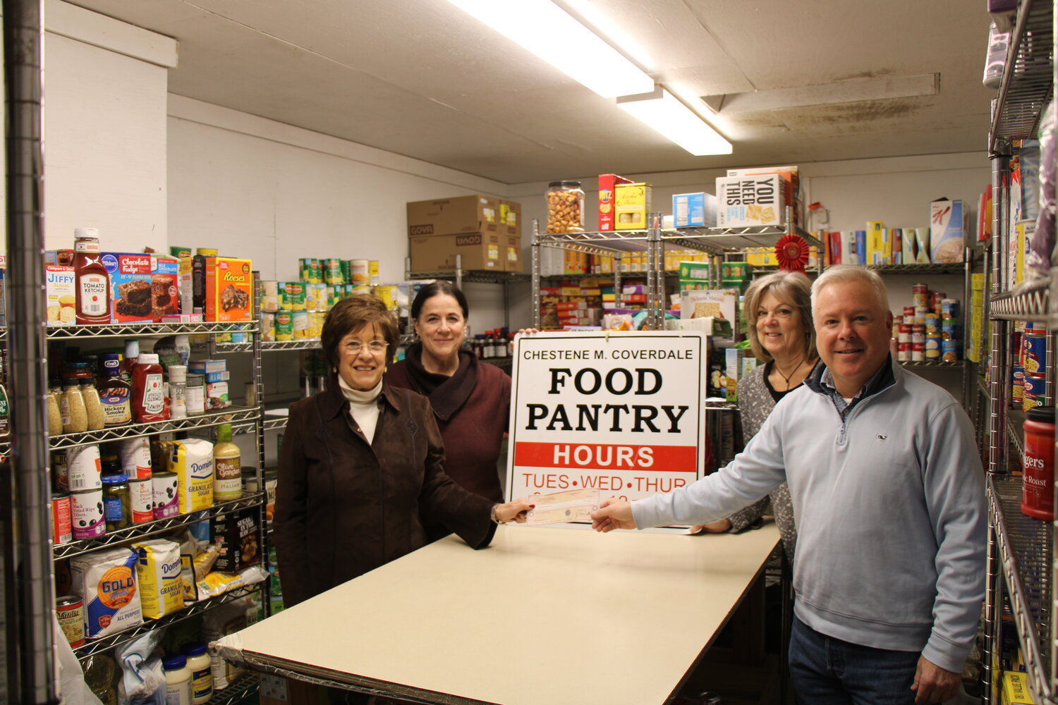 Suffolk County News publisher Terry Tuthill presents Charlene Lehmann, director of the Chestene M. Coverdale Pantry in Sayville, with a donation from the paper’s Holiday Greeting Fund. Also pictured are volunteers Sarah Isaacson (left) and Mary O’Connor (right).